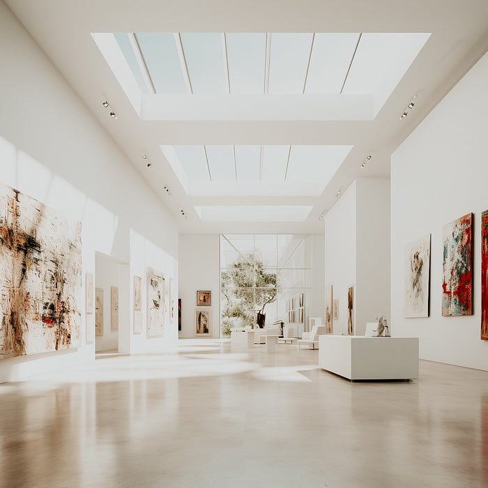 Interior view of a museum with natural lighting and multiple paintings displayed on the walls.