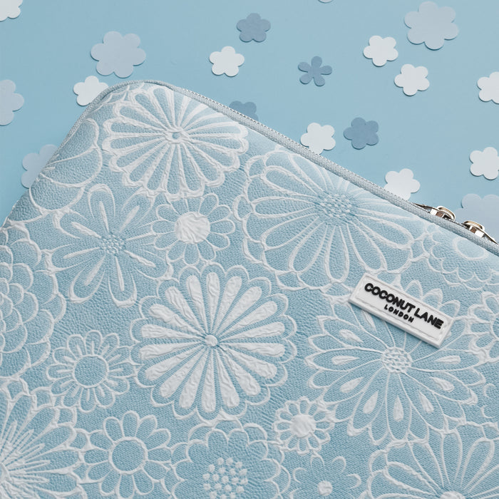 Light blue floral laptop sleeve on blue background with paper flower decorations.
