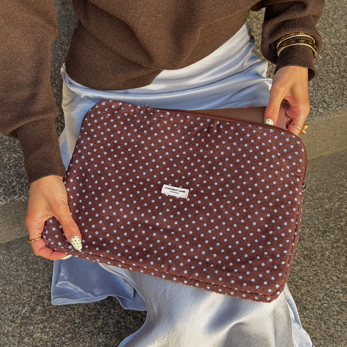 Girl sat holding Blue and Brown Polka Dot Laptop Sleeve wearing her blue silk skirt