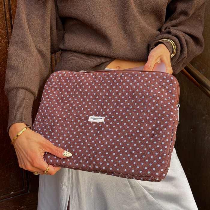 Girl in blue silk skirt holding laptop sleeve in blue and brown polka dot