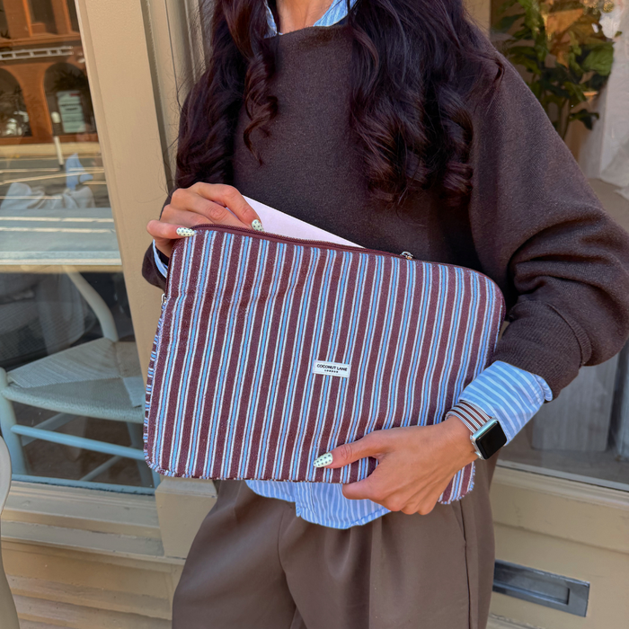 Girl holding Brown and Blue Stripe Laptop Sleeve stood outside a cafe