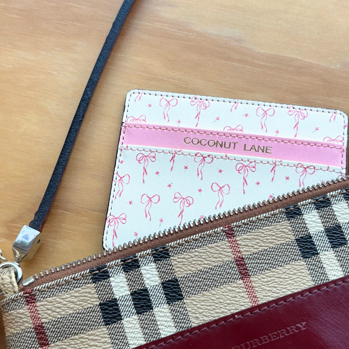 Pink Coconut Lane Dainty Bows card holder inside a beige vegan Burberry wallet on a wooden table.