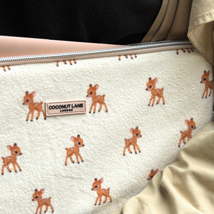 Cream fleece laptop sleeve with small deer print, partially covered by a beige jacket.