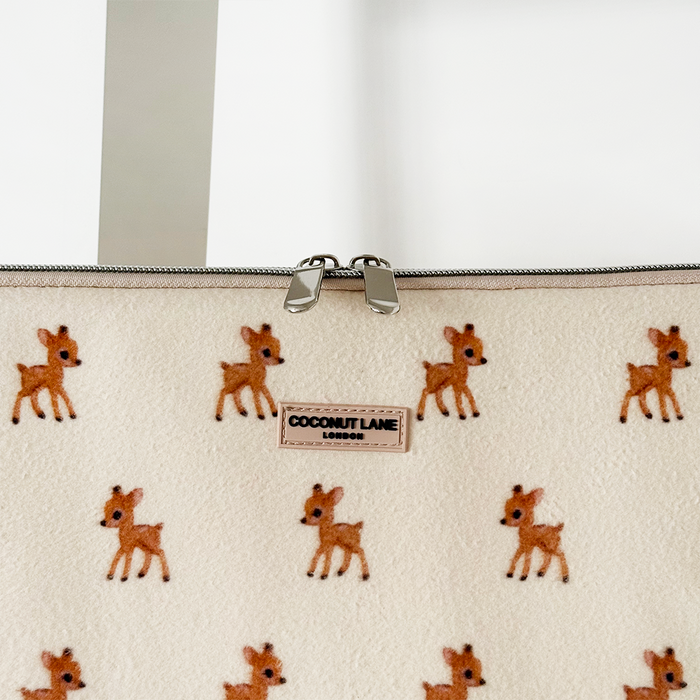Cream laptop sleeve with a small cartoon deer, silver zipper, and front label.