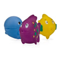 The Nuby Fun Fish Squirters - 3 pack features colorful rubber sea creature bath toys—a blue whale, a purple spotted fish, and a yellow fish—all with big eyes, ideal as a baby development toy on a white background.