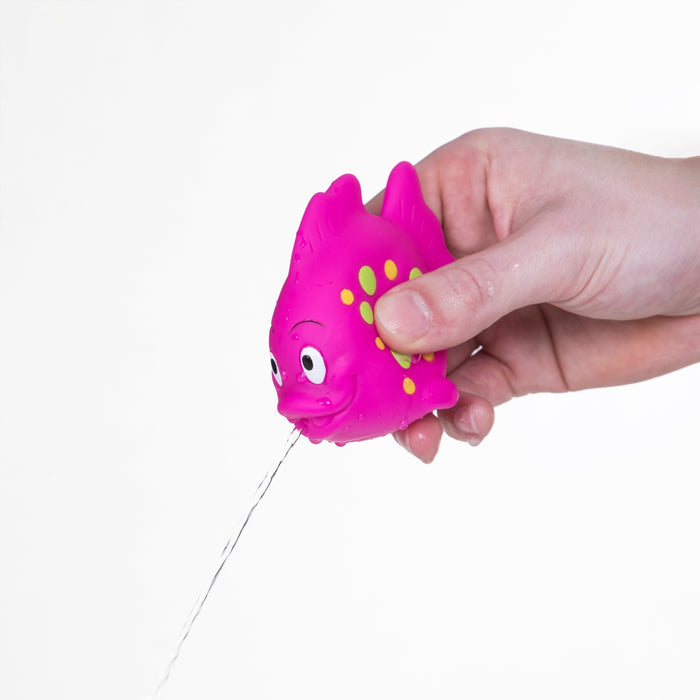 A hand squeezes a pink Fun Fish Squirter bath toy by Nuby, spraying water from its mouth on a white background—perfect as a playful baby development toy. Available in a 3 pack.