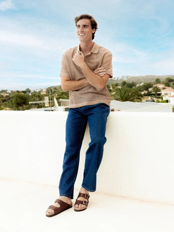 Man standing on a rooftop with a scenic view in the background wearing genuins leather sandals
