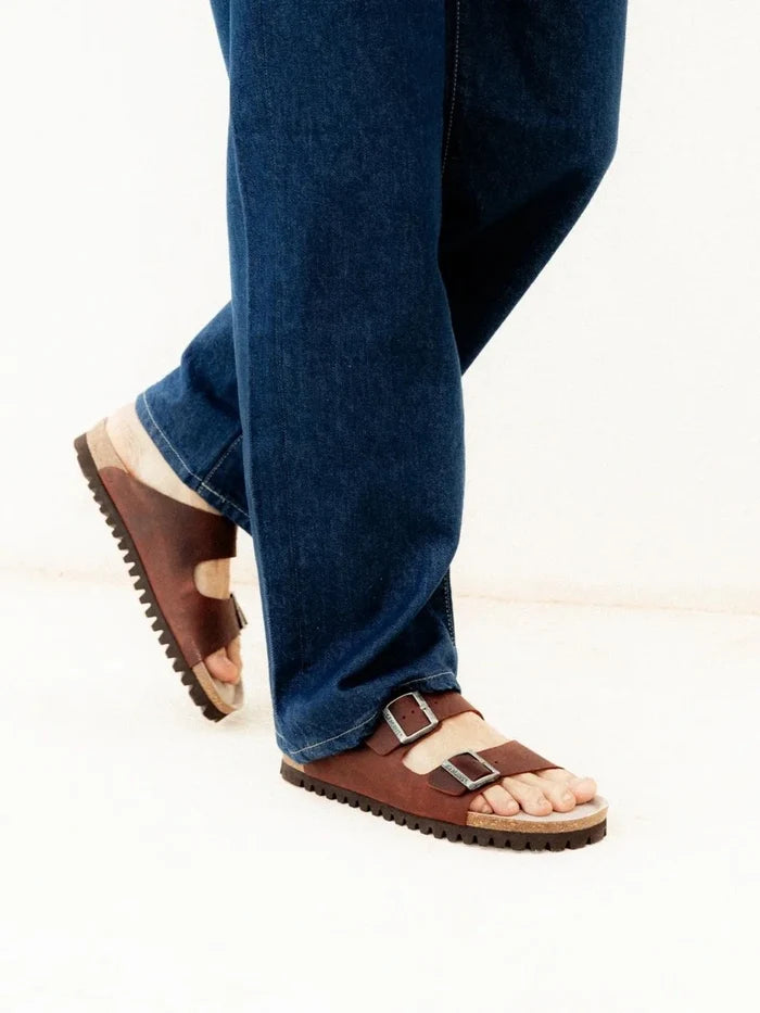Genuins hawaii leather sandals worn with blue jeans on a white background