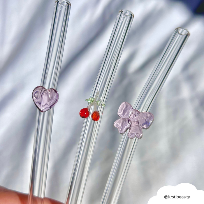 Set of three clear glass straws, each featuring a small pink bow charm.