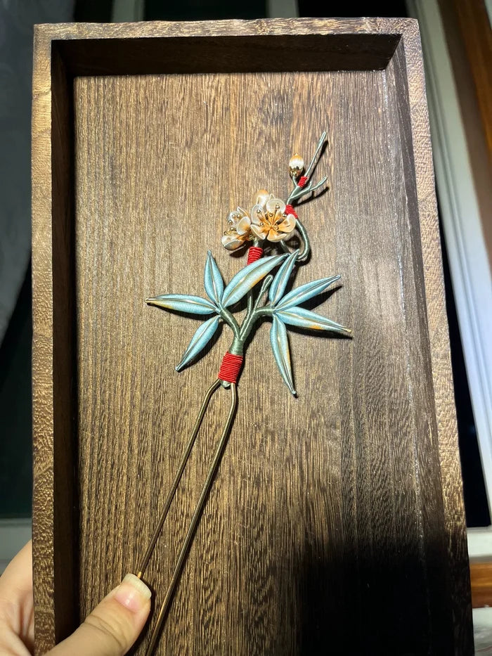 A handmade Chanhua hairpin with bamboo and plum blossom design on a wooden background-2