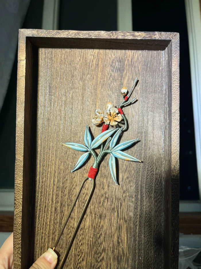 A handmade Chanhua hairpin with bamboo and plum blossom design on a wooden background-3