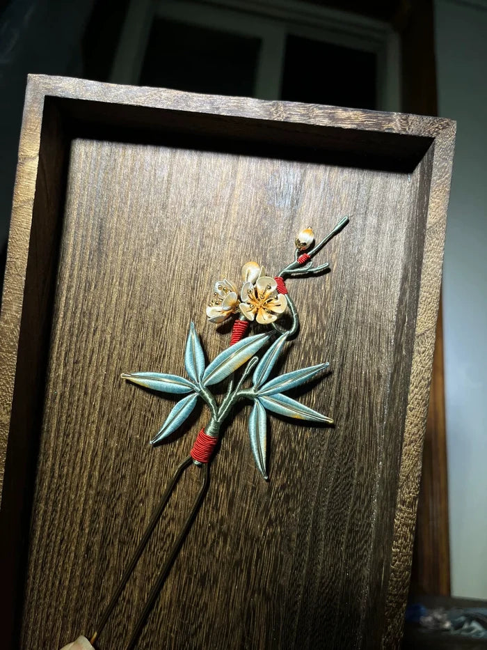 A handmade Chanhua hairpin with bamboo and plum blossom design on a wooden background-4
