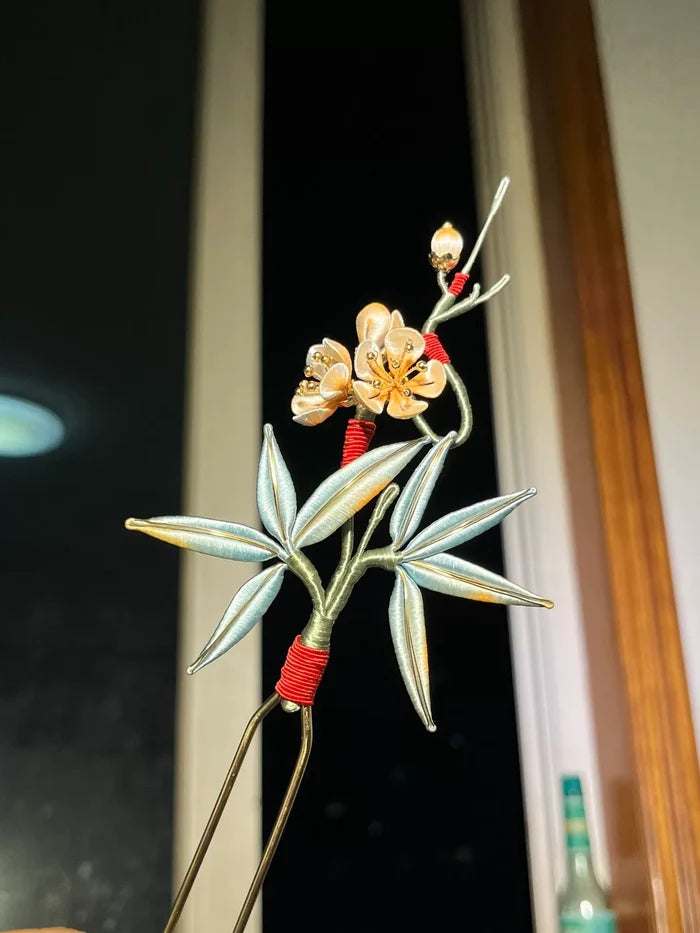 A handmade Chanhua hairpin with bamboo and plum blossom design on a wooden background-5