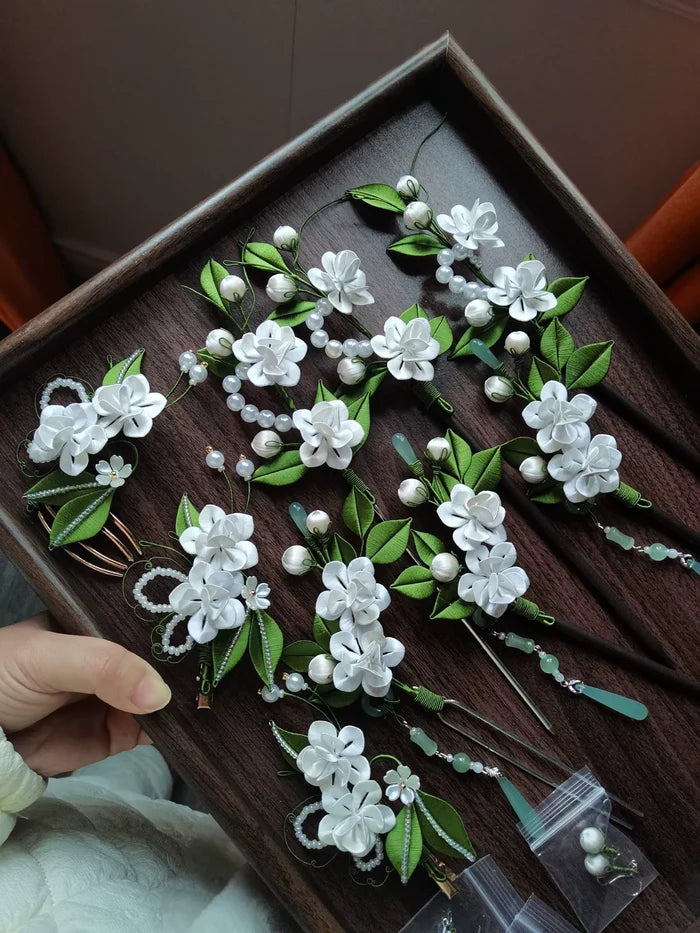 A set of handmade Chanhua jasmine - themed hair accessories in a wooden tray