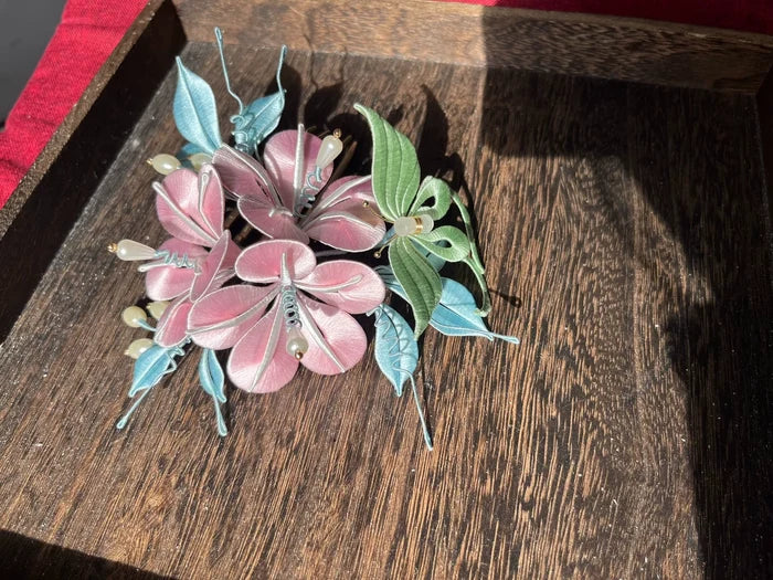 A handmade Chanhua morning glory hairpin with pink flowers and blue - green leaves on a wooden tray