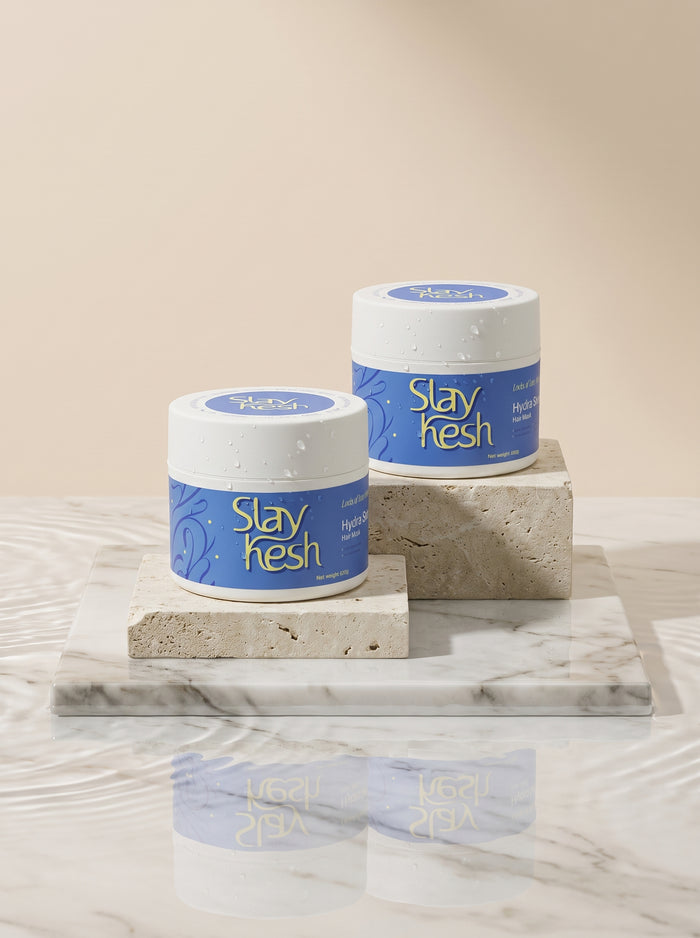 Slaykesh Hydration Duo Two Hair Mask jars displayed on stone pedestals in water
