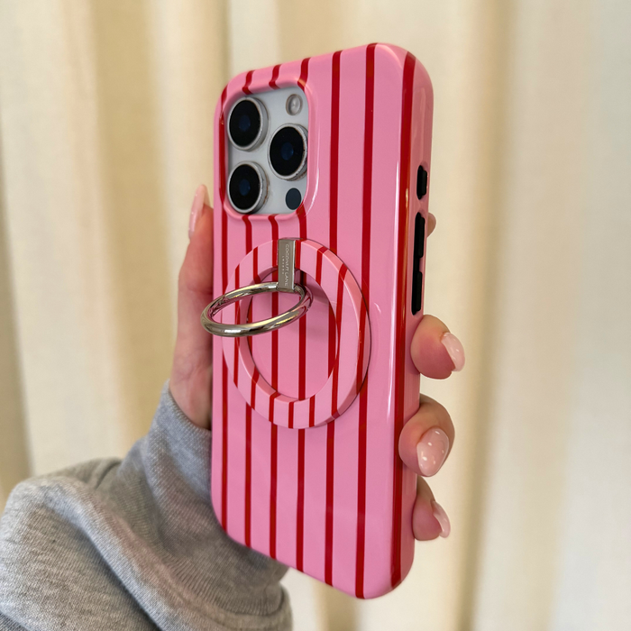 Hand holds phone with Coconut Lane MAGSAFE® cherry stripes ring on pink and red striped case.