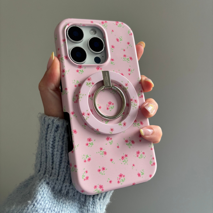 Hand holding a pink floral Coconut Lane MAGSAFE® phone case with ring, shown against a plain gray background.