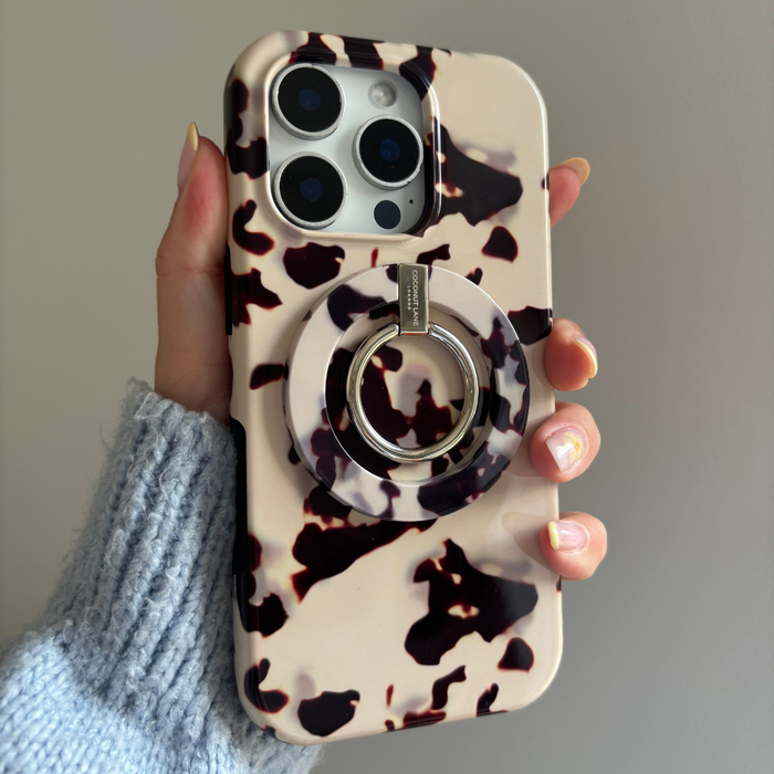 Hand holding a phone with an ivory tortoiseshell MAGSAFE® ring holder attached.