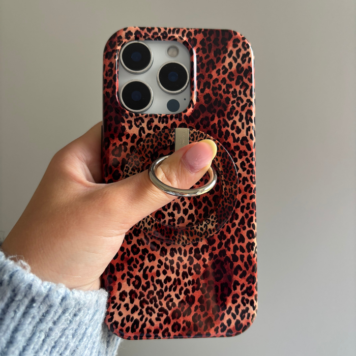 Hand holding Coconut Lane MAGSAFE® Leopard Phone Ring on a matching leopard print phone case against a plain background.
