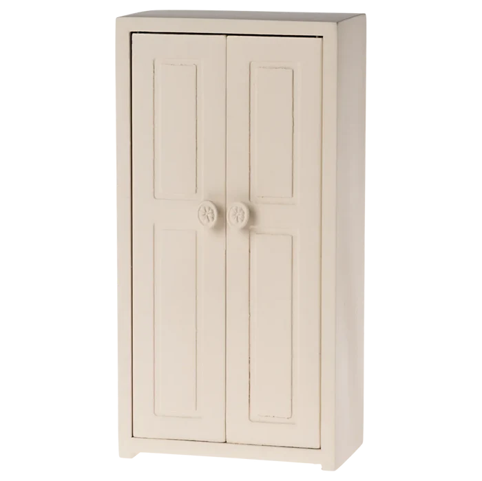 A small toy closet in a cream color with two doors and three golden hangers inside.