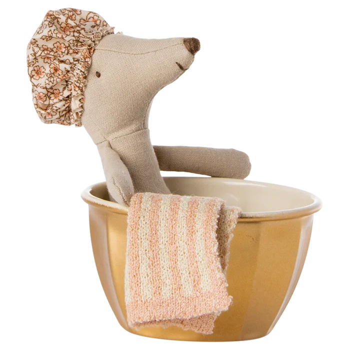 A toy mouse with a shower cap standing in a golden metal bathtub with a towel hanging on the side.