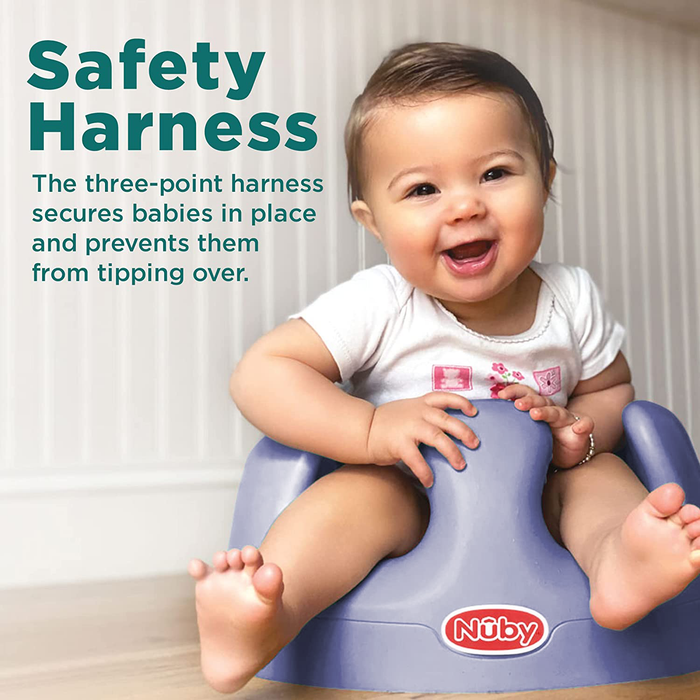 A smiling baby sits in a blue My Floor Seat with an ergonomic design and a three-point safety harness that keeps infants secure and helps prevent tipping.