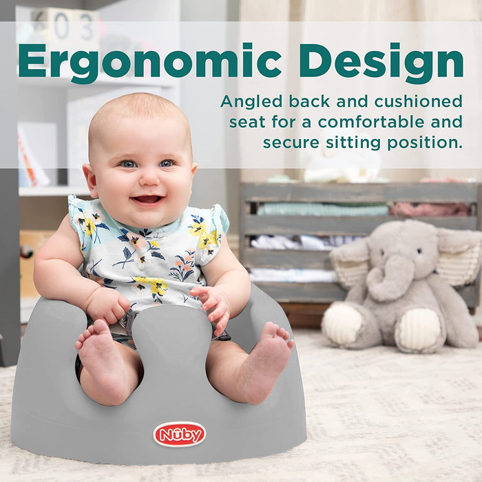 A smiling baby sits in the gray My Floor Seat with an angled back and cushioned base for ergonomic comfort and security. An elephant plush is in the background. Text: Ergonomic Design—angled back and cushioned seat for secure sitting.
