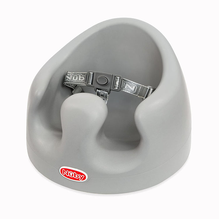 The My Floor Seat is a gray ergonomic baby seat with a high back, leg openings, and built-in safety harness. Its rounded design offers support, and the Nuby logo appears on the front.