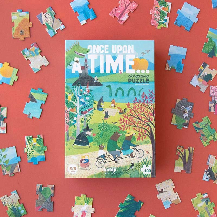 A puzzle box with a colorful illustration of fairy tale characters in a village setting, surrounded by puzzle pieces with various illustrations in the background.