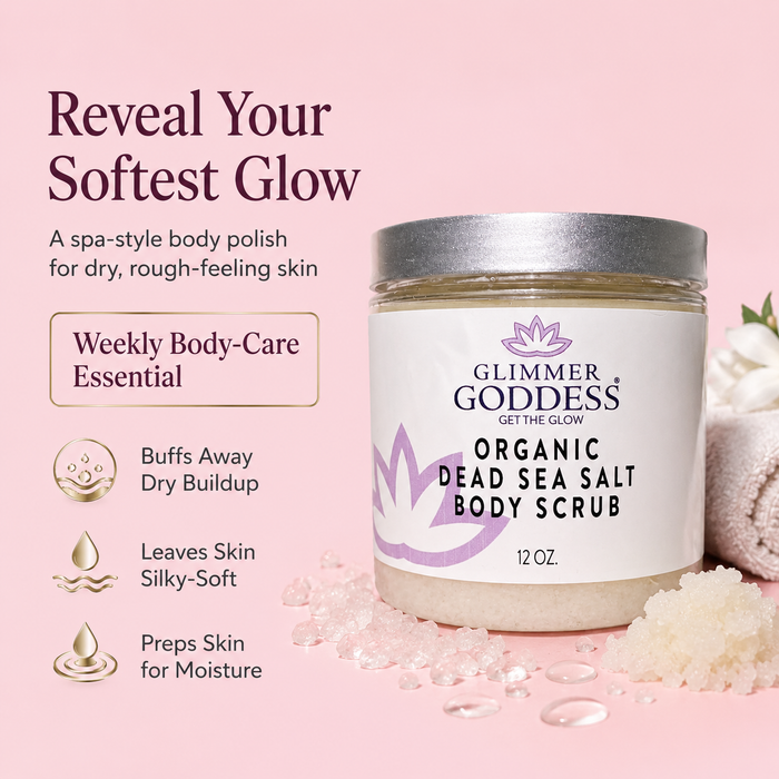Glimmer Goddess Organic Dead Sea Salt Body Scrub in a clear jar with a white label and silver lid, shown on a soft pink background with spa-style body scrub crystals and rolled towel props. Text on the left describes benefits.