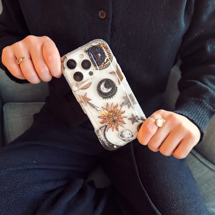 Clear phone case with sun, moon, and star designs held by a person in dark clothing.