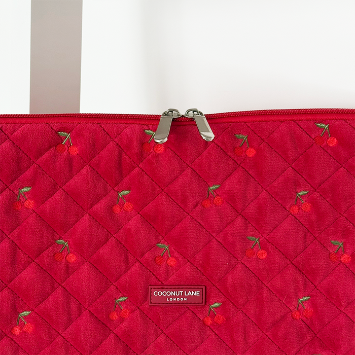 Cherry red quilted velvet laptop sleeve with a silver zipper and center Coconut Lane label.