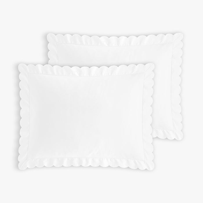 Two white scalloped pillowcases on a light gray background