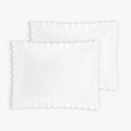 Two white scalloped pillowcases on a light gray background