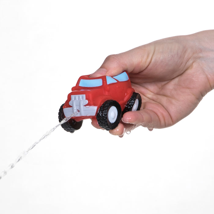 A hand squeezes a red Nuby Squirt Wheels Bath Squirters car, spraying water from the front against a plain white background—perfect for imaginative play. Comes in a 4 pack.