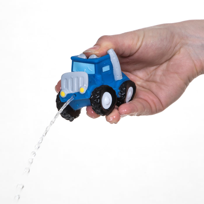 A hand squeezes a blue Nuby Squirt Wheels Bath Squirters truck, spraying water from the front—perfect for imaginative play. Shown against a white background. Set includes 4 bath squirters.