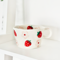 White ceramic mug with red strawberry and pink flower pattern by Coconut Lane.