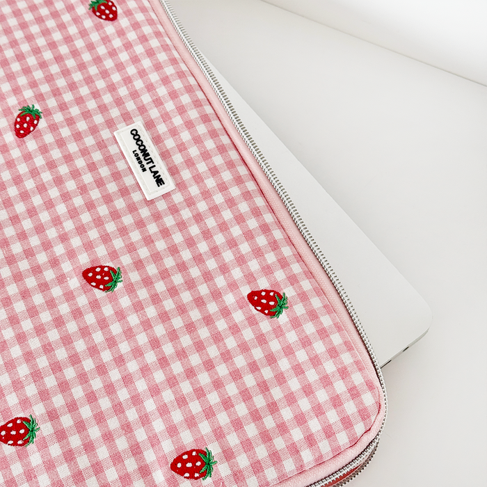 Pink gingham laptop sleeve with embroidered strawberries and a silver zip.