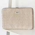 Cream and gold textured tweed laptop sleeve with zipper, placed on a white shelf.