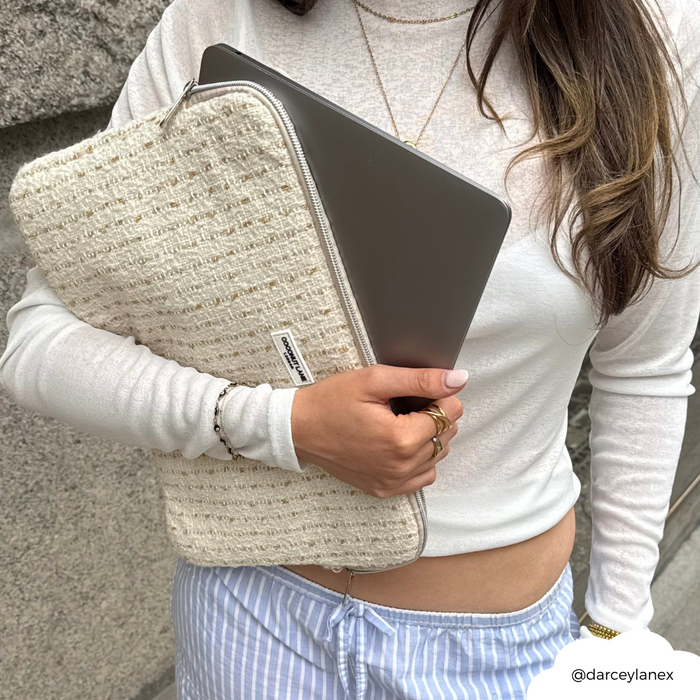 Woman in a white top holds a Vanilla Textured Tweed Laptop Sleeve; she wears striped pants and gold rings.
