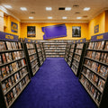 DVD shelves arranged in a store with color-coded sections for new releases, action, drama, and more.