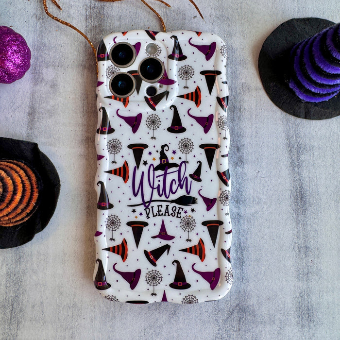 Witch Please Wavy Luxe MagSafe iPhone case shown flat on stone with purple pumpkins, displaying the full cream witch hat print.